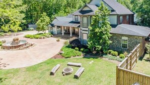 A two-story house with a stone exterior, a covered porch, and a landscaped yard with a fountain.