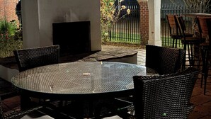An outdoor patio with a round table and chairs, a built-in grill, and a stone wall.