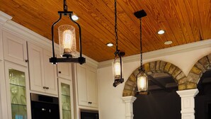 A modern kitchen with white cabinetry, a central island with a stainless steel stove, and pendant lighting.
