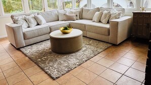 A living room with a sectional sofa, a round coffee table, and a patterned rug.
