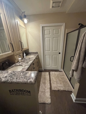 Un baño con lavamanos, espejo, toallero y puerta.