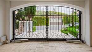 A gated entrance with a driveway leading to a house. - Luxurious 5-bedroom villa with AC, fitness room in Beverly Hills (Beverly Hills)