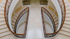 A grand staircase with ornate railings, a chandelier, and a green room in the background. - Luxurious 5-bedroom villa with AC, fitness room in Beverly Hills (Beverly Hills)
