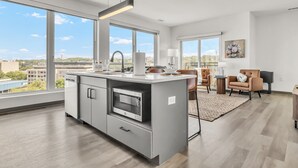 Een moderne keuken met een groot eiland, een ingebouwde oven en uitzicht op de stad.