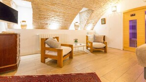 A cozy room with a vaulted ceiling, wooden furniture, a flat-screen TV, and a small table with a vase.