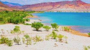 A desert landscape with a river, green vegetation, and distant mountains. - Luxury RV Camper Southern UTAH! (Toquerville)