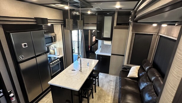 A compact RV kitchen with a central island, a built-in oven, and a microwave. - Luxury RV Camper Southern UTAH! (Toquerville)