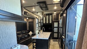 A compact RV kitchen with a central island, a dining area, and a seating space. - Luxury RV Camper Southern UTAH! (Toquerville)