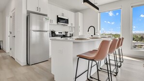 A modern kitchen with white cabinetry, stainless steel appliances, and a large window offering a view of the sky and landscape. - Peaceful & Relaxing 2BR | Cleveland Clinic (Cleveland)