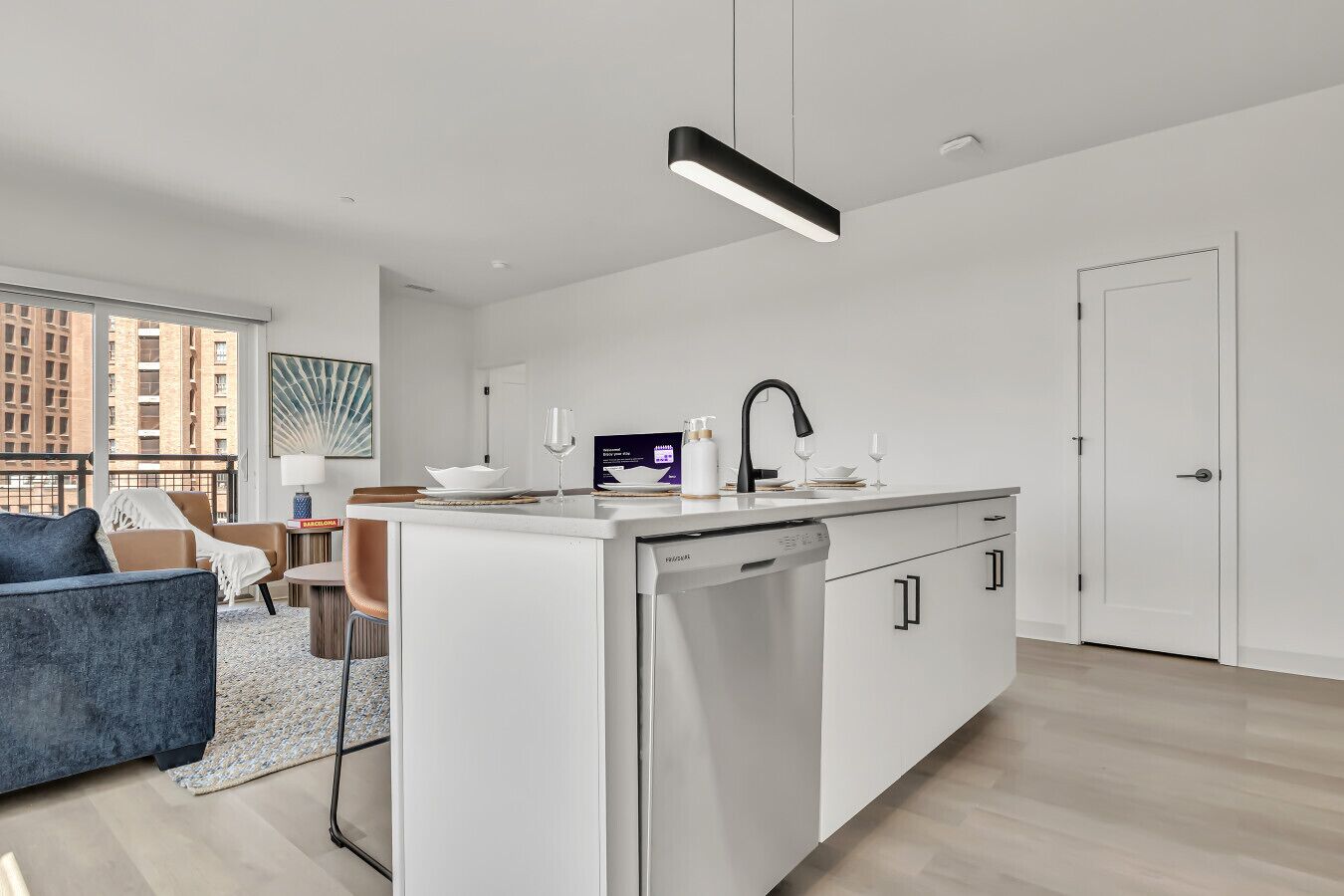 A modern kitchen with a dishwasher, a sink, and a dining area with a chair and a table.