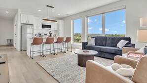A modern living space with a kitchen, bar area, and seating area with a view. - Peaceful & Relaxing 2BR | Cleveland Clinic (Cleveland)