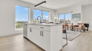 A modern kitchen with large windows, a dining area with a view, and a living space with a sofa and a coffee table. - Peaceful & Relaxing 2BR | Cleveland Clinic (Cleveland)