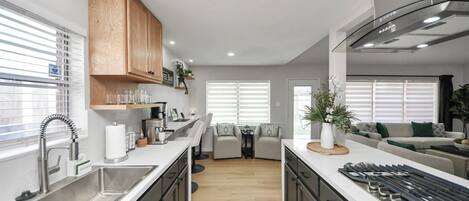 A modern kitchen with a central island, built-in appliances, and a dining area with a sofa and chairs.