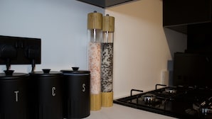 A kitchen with black storage containers labeled T, C, and S, and two cylindrical containers with wooden tops. - 2 bed House in City Centre - Offers for Long Stays (Nottingham)