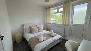A bedroom with a bed, bedside tables, a chair, and a window with curtains. - 2 bed House in City Centre - Offers for Long Stays (Nottingham)