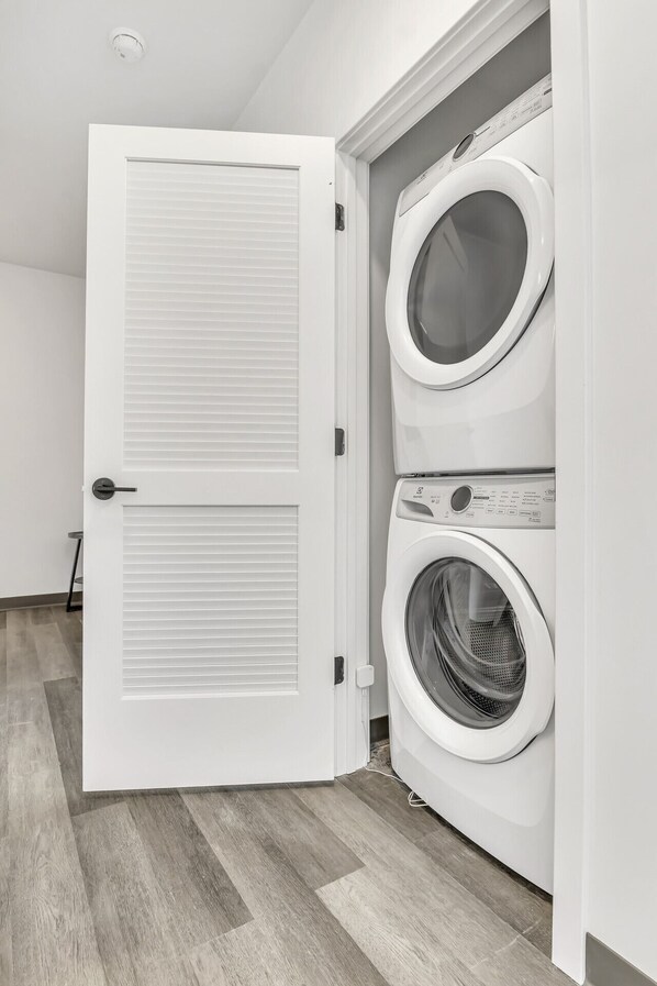 A laundry room with a double door and two stacked front-loading washing machines.