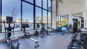 Une salle de sport équipée de divers appareils d’exercice, dotée de grandes fenêtres et offrant une vue sur l’extérieur.
