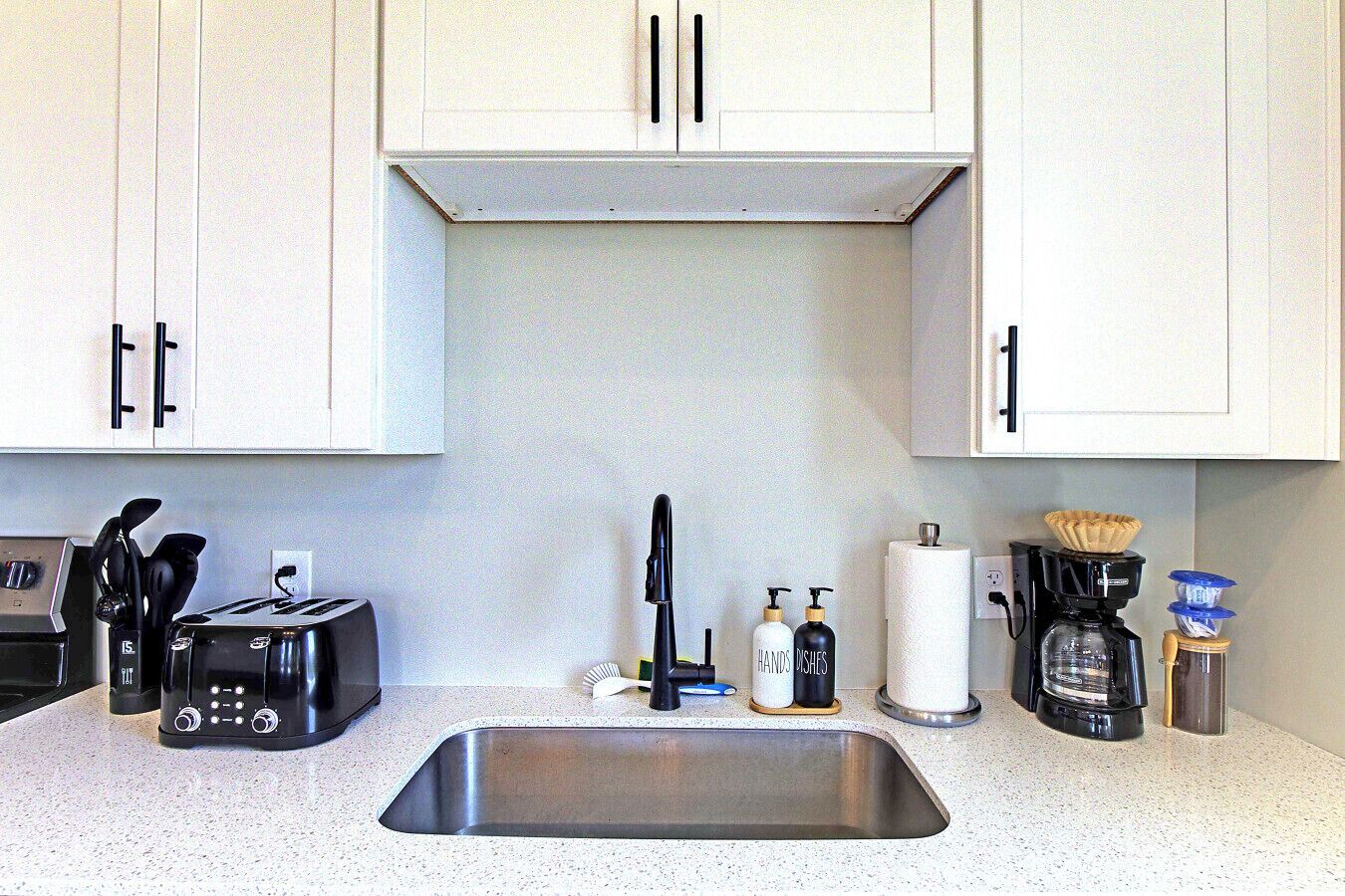 A kitchen with a stainless steel sink, a toaster, a coffee maker, and a knife block.
