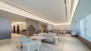 A modern lounge area with a sofa, chairs, and round tables. - Ji Hotel Guangzhou Huangpu East Metro Station (Guangzhou)
