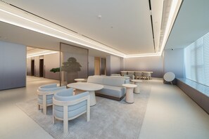 A modern lounge area with a sofa, chairs, and round tables. - Ji Hotel Guangzhou Huangpu East Metro Station (Guangzhou)
