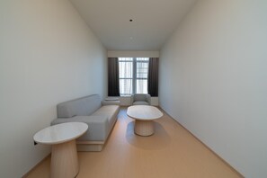 A modern, minimalist living room with a sofa, two round tables, and a large window with curtains. - Ji Hotel Guangzhou Huangpu East Metro Station (Guangzhou)