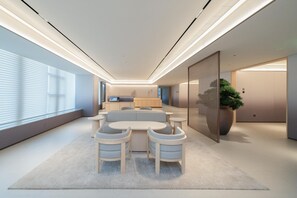 A modern interior with a sofa set, a dining table, and a large potted plant. - Ji Hotel Guangzhou Huangpu East Metro Station (Guangzhou)