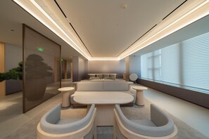 A modern, well-lit lounge area with a sofa, round tables, and a large window with blinds. - Ji Hotel Guangzhou Huangpu East Metro Station (Guangzhou)