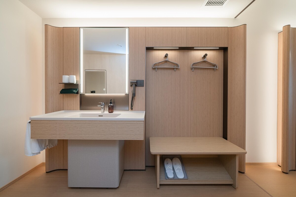 Une salle de bain moderne équipée d’un lavabo, d’un miroir, d’un porte-serviettes et d’un espace de rangement pour les chaussures.