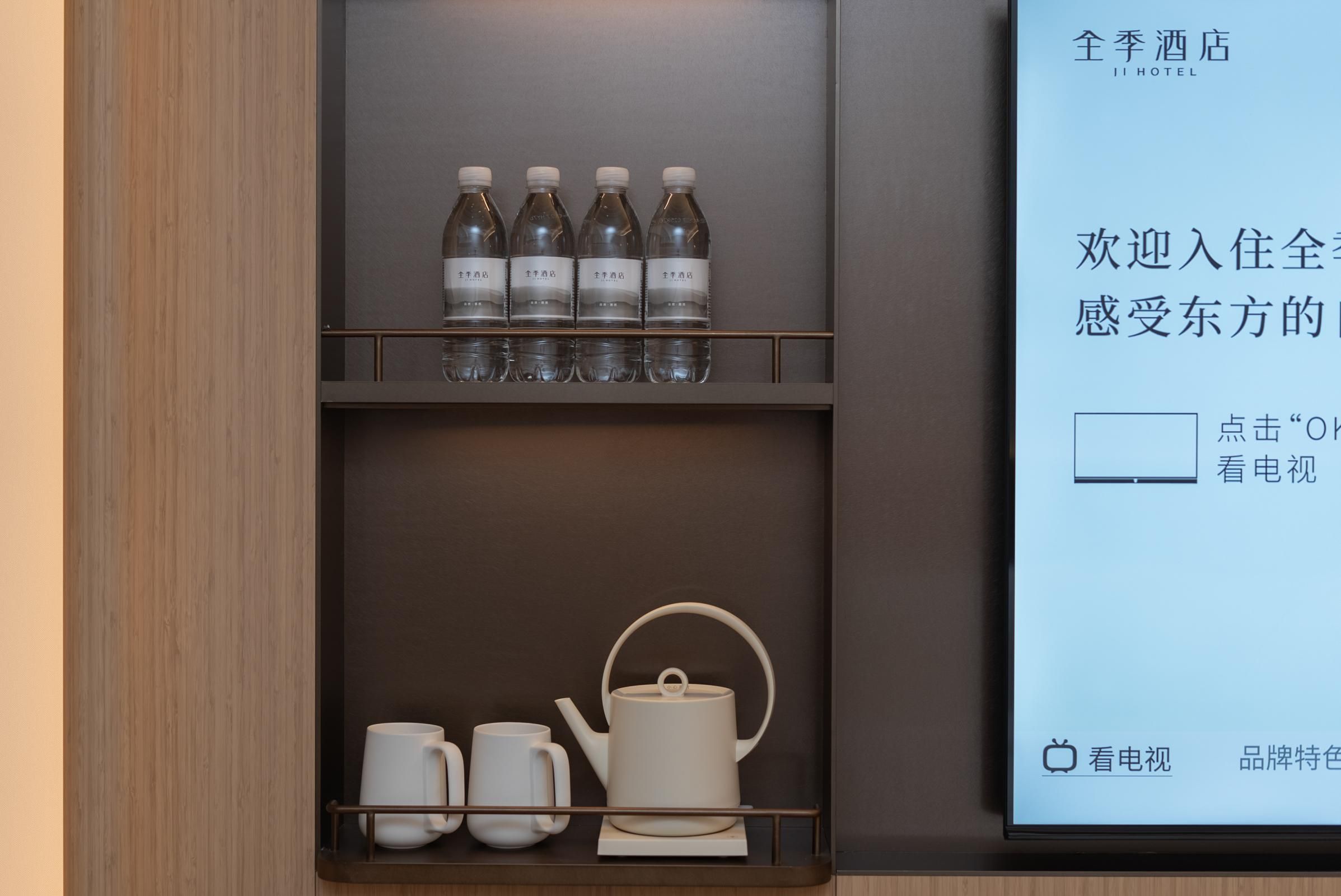 Minibar de hotel con agua embotellada y juego de té.