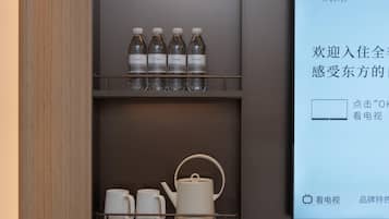 Minibar de hotel con agua embotellada y juego de té.