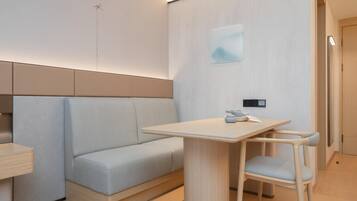 Quarto moderno e minimalista com um sofá de cor clara, uma mesa de madeira e uma cadeira.