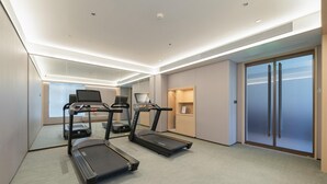 Ein modernes Hotelzimmer mit Laufband, Ergometer und großem Spiegel.