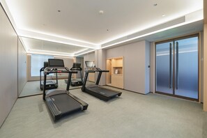 A modern hotel room with a treadmill, exercise bike, and a large mirror. - Ji Hotel Guangzhou Huangpu East Metro Station (Guangzhou)