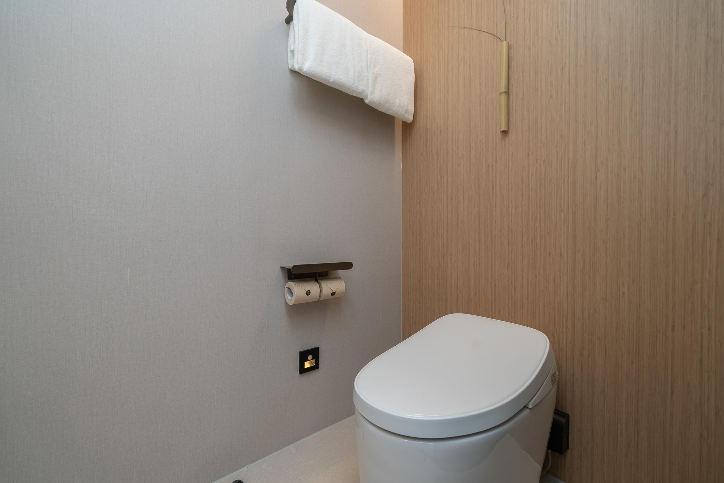 A modern bathroom with a toilet, a towel rack, and a toilet paper holder.