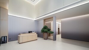 A modern reception area with a reception desk, a large potted plant, and a minimalist interior design. - Ji Hotel Guangzhou Huangpu East Metro Station (Guangzhou)