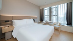 Ein Hotelzimmer mit einem großen Bett, einem Nachttisch und einem kleinen Tisch mit Stühlen.