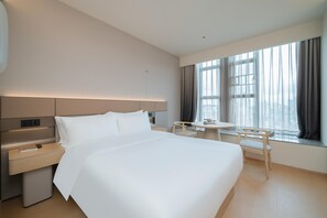 Une chambre d’hôtel avec un grand lit, une table de chevet et une petite table avec des chaises.