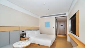 Et moderne hotelværelse med en stor seng, sengeborde, et lille rundt bord og et fjernsyn.