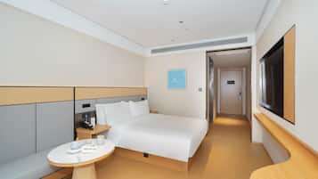 Una habitación de hotel moderna con una cama grande, mesitas de noche, una pequeña mesa redonda y un televisor.