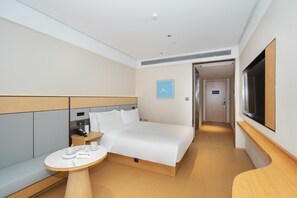 Ein modernes Hotelzimmer mit einem großen Bett, Nachttischen, einem kleinen runden Tisch und einem Fernseher.