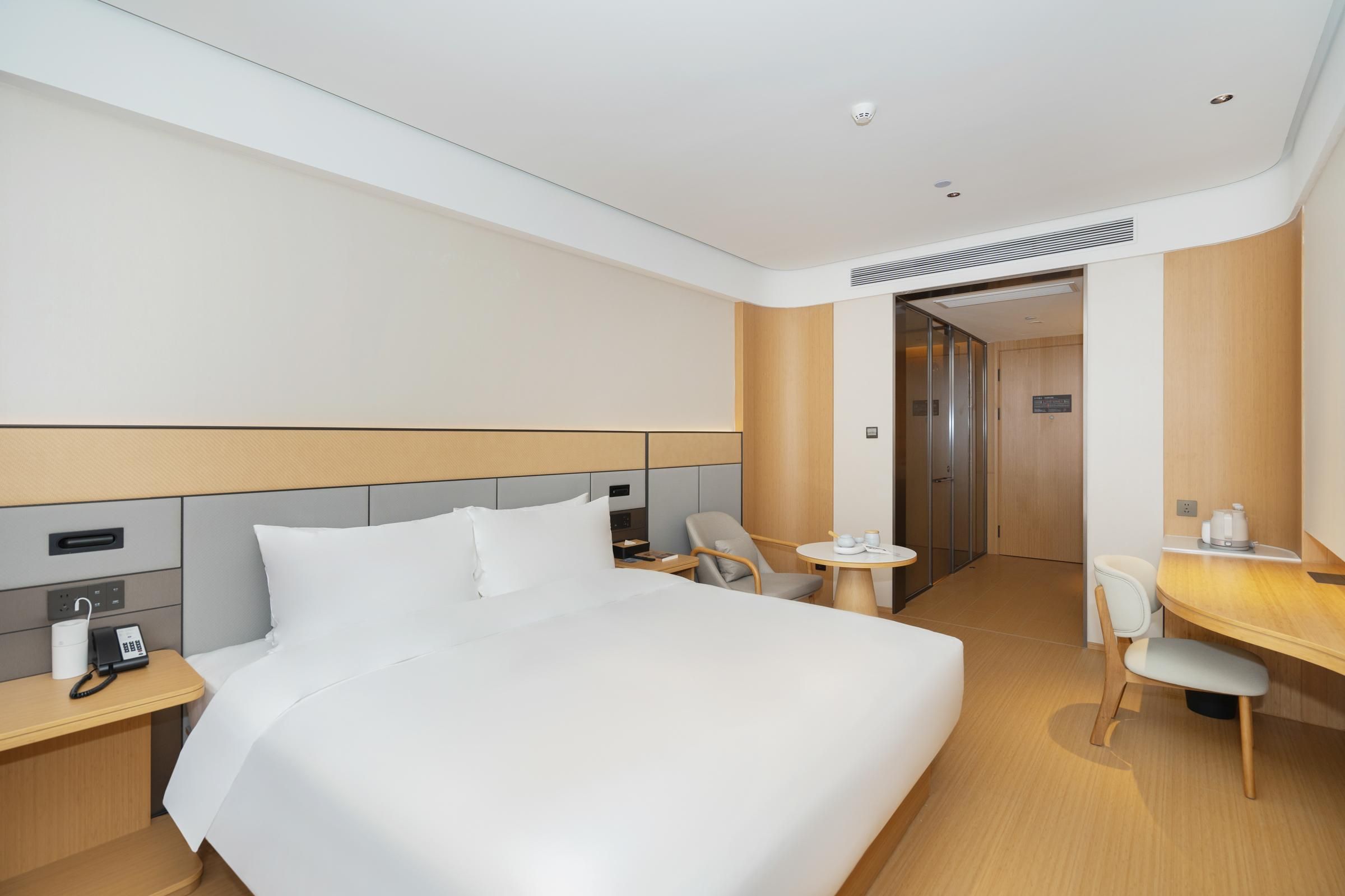 Ein modernes Hotelzimmer mit einem großen Bett, Nachttischen, einem Schreibtisch und einem Stuhl.