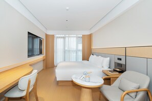 Et moderne hotelværelse med en stor seng, et skrivebord, en stol og et lille bord.