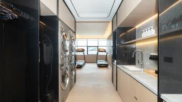 Un lavadero moderno con varias lavadoras y secadoras, un lavabo y un ventanal que proporciona luz natural.
