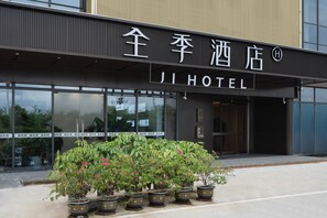 L'ingresso di un hotel con un cartello che riporta "JI HOTEL" e piante in vaso davanti.