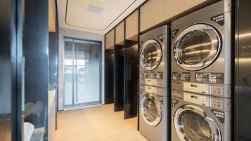 A modern laundry facility with multiple washing machines, a glass door entrance, and a wooden floor.
