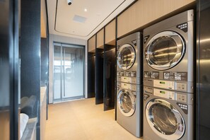 A modern laundry facility with multiple washing machines, a glass door entrance, and a wooden floor. - Ji Hotel Guangzhou Huangpu Wenchong (Guangzhou)