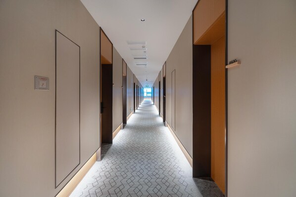 A long, narrow hallway with doors on both sides, leading to individual rooms. - Ji Hotel Guangzhou Huangpu Wenchong (Guangzhou)