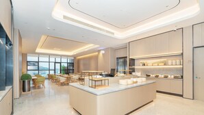 A modern kitchen with a central island, built-in appliances, and a large window providing natural light. - Ji Hotel Guangzhou Huangpu Wenchong (Guangzhou)