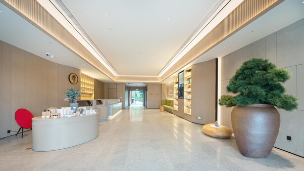 A modern hotel lobby with a reception desk, a large potted plant, and a red chair. - Ji Hotel Guangzhou Huangpu Wenchong (Guangzhou)