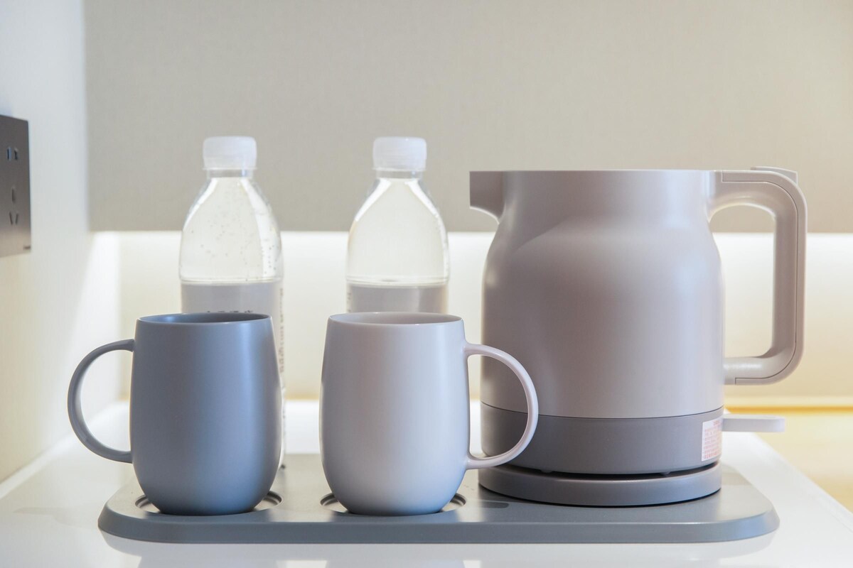 A kitchen counter with two mugs and two water bottles.